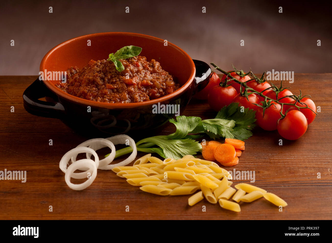 Penne pasta in tomato sauce with chicken, tomatoes decorated with parsley on a wooden table Stock Photo