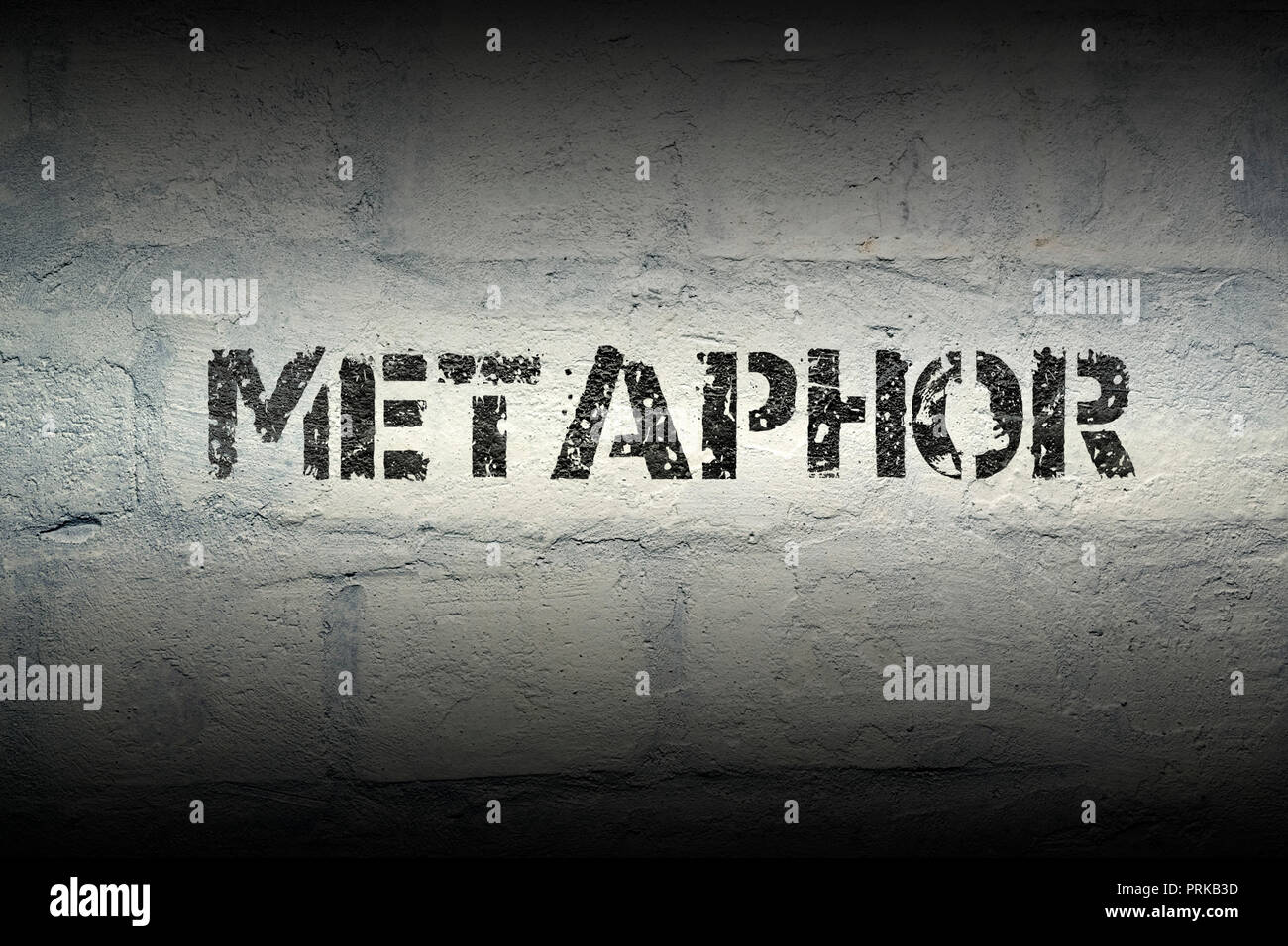 metaphor word stencil print on the grunge white brick wall Stock Photo