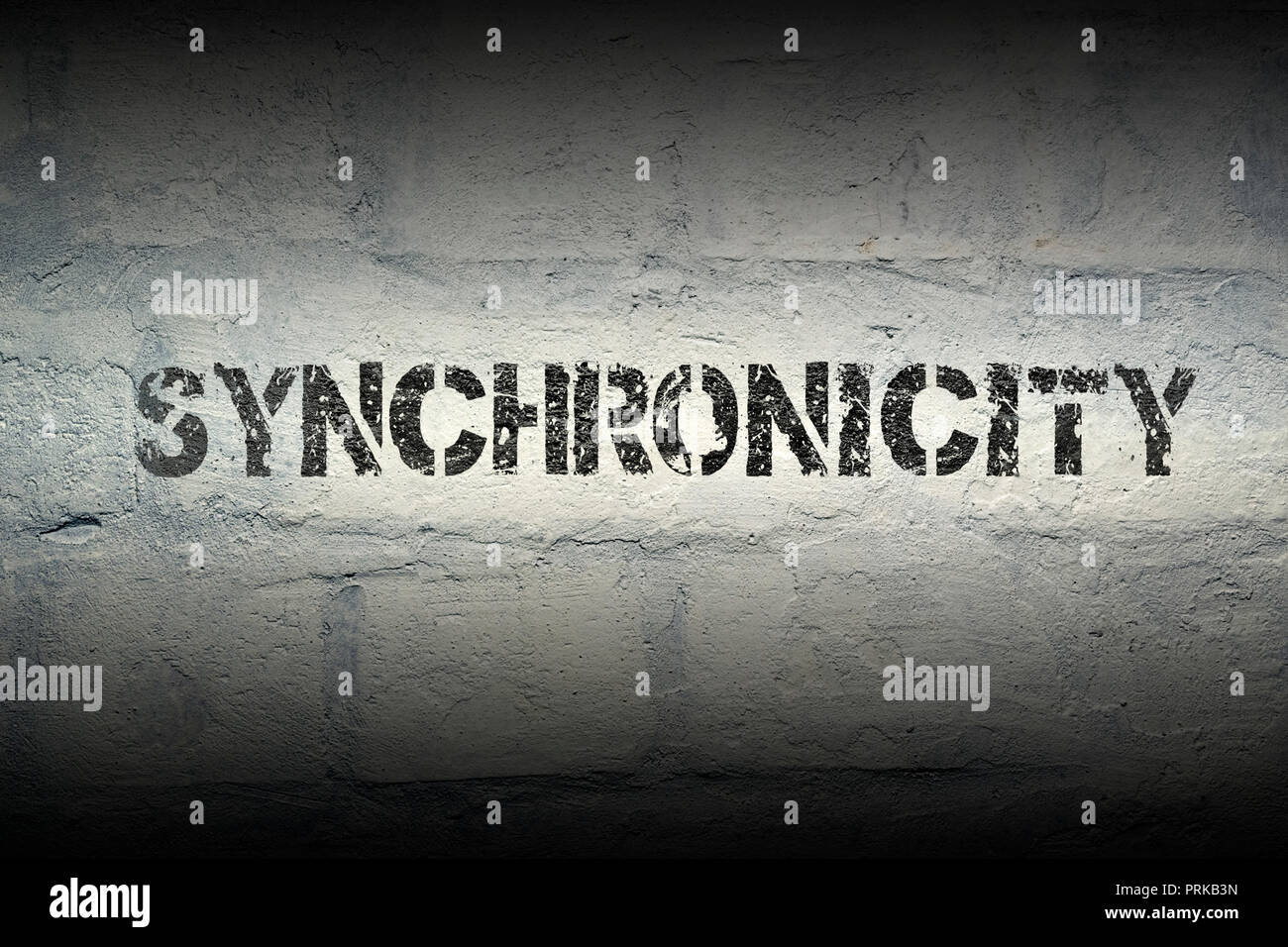 synchronicity stencil print on the grunge white brick wall Stock Photo