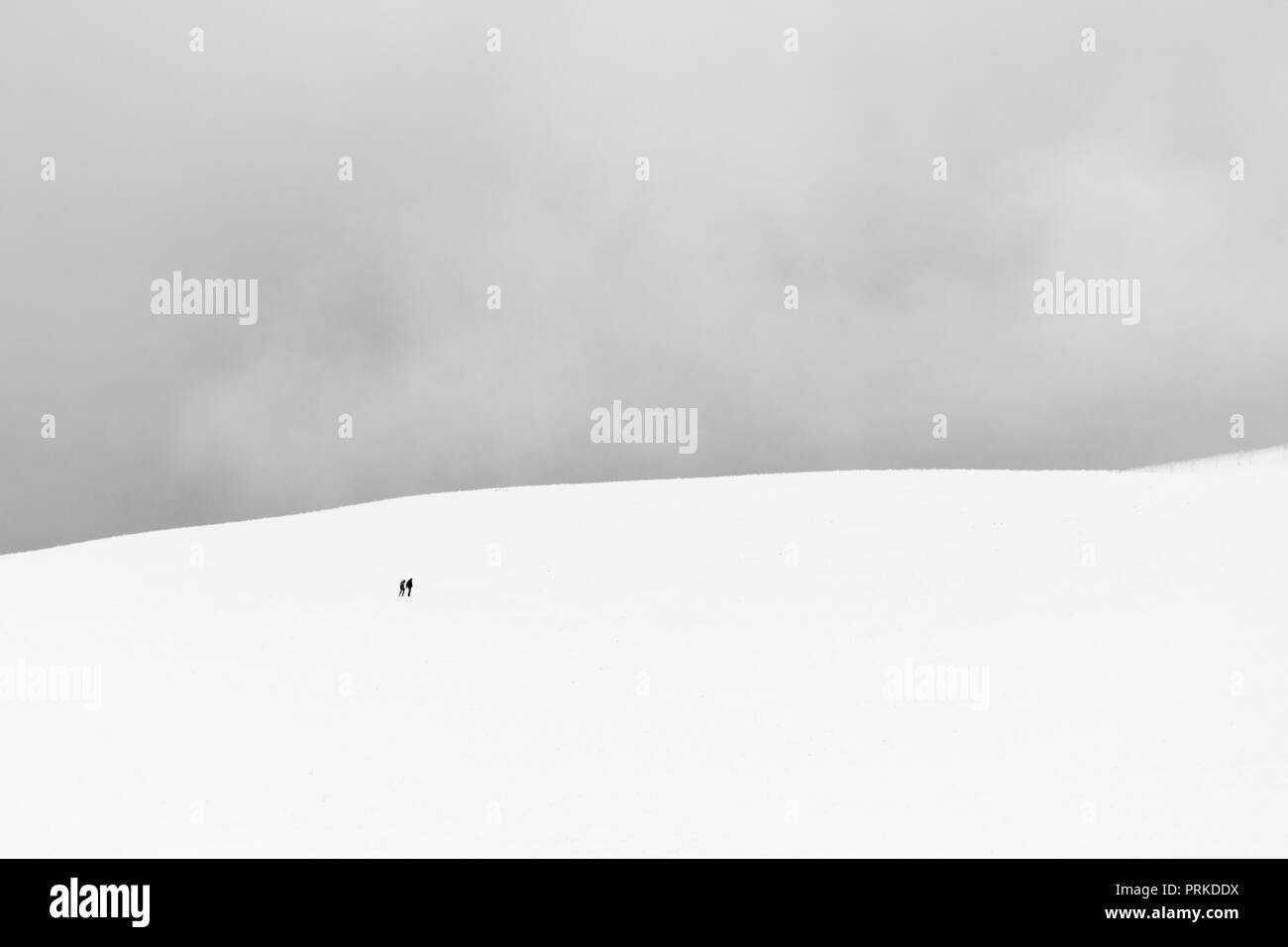 A very minimalistic view of two distant people over a mountain covered by snow Stock Photo