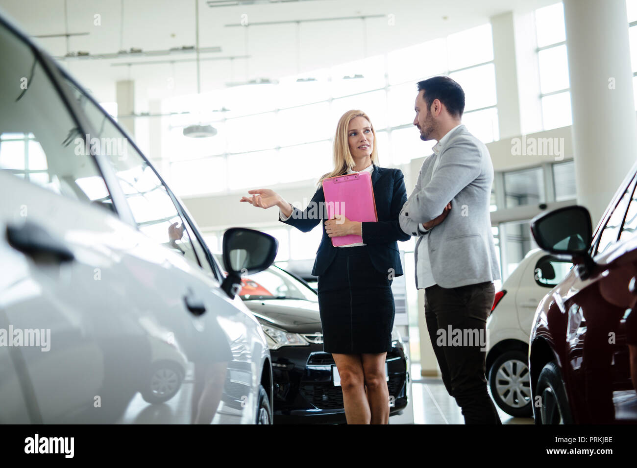 Professional salesperson during work with customer at car dealership. Stock Photo