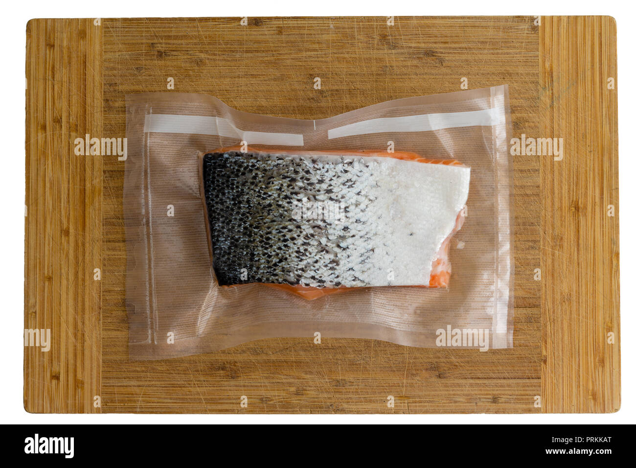 Top view of a fresh raw portion of Atlantic salmon vacuum packed in clear plastic ready for freezing or sous-vide cooking on a wooden board Stock Photo