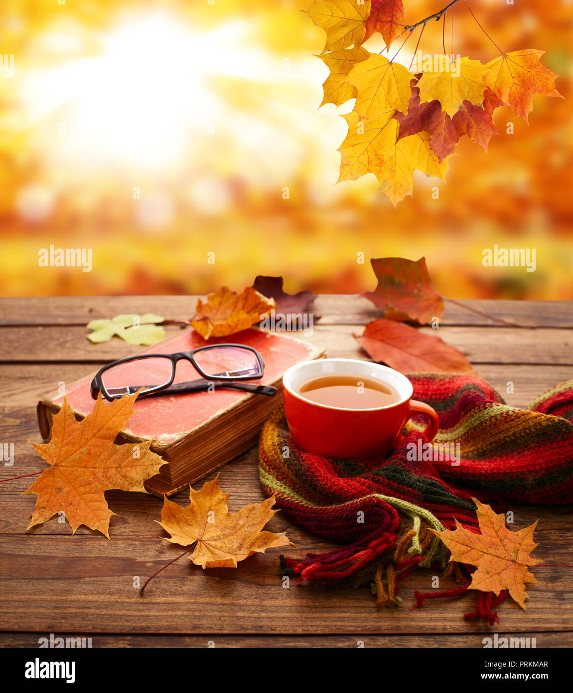 Autumn background. Autumn leaves, book and cup of tea on wooden table closeup in park. Stock Photo