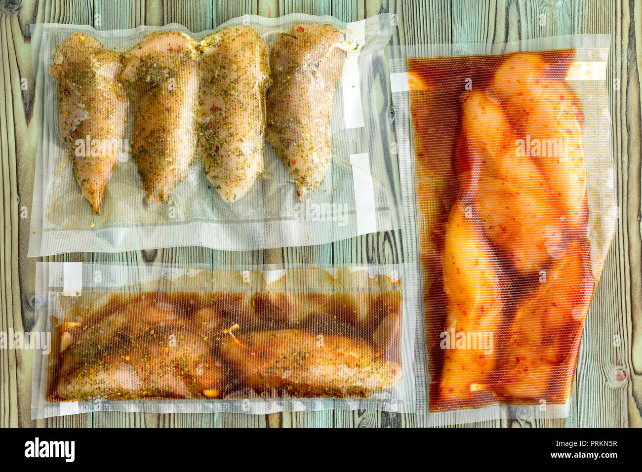 Vacuum packed portions of lean chicken breast with assorted marinades and seasoned with spices and herbs ready for freezing or sous-vide cooking on ru Stock Photo
