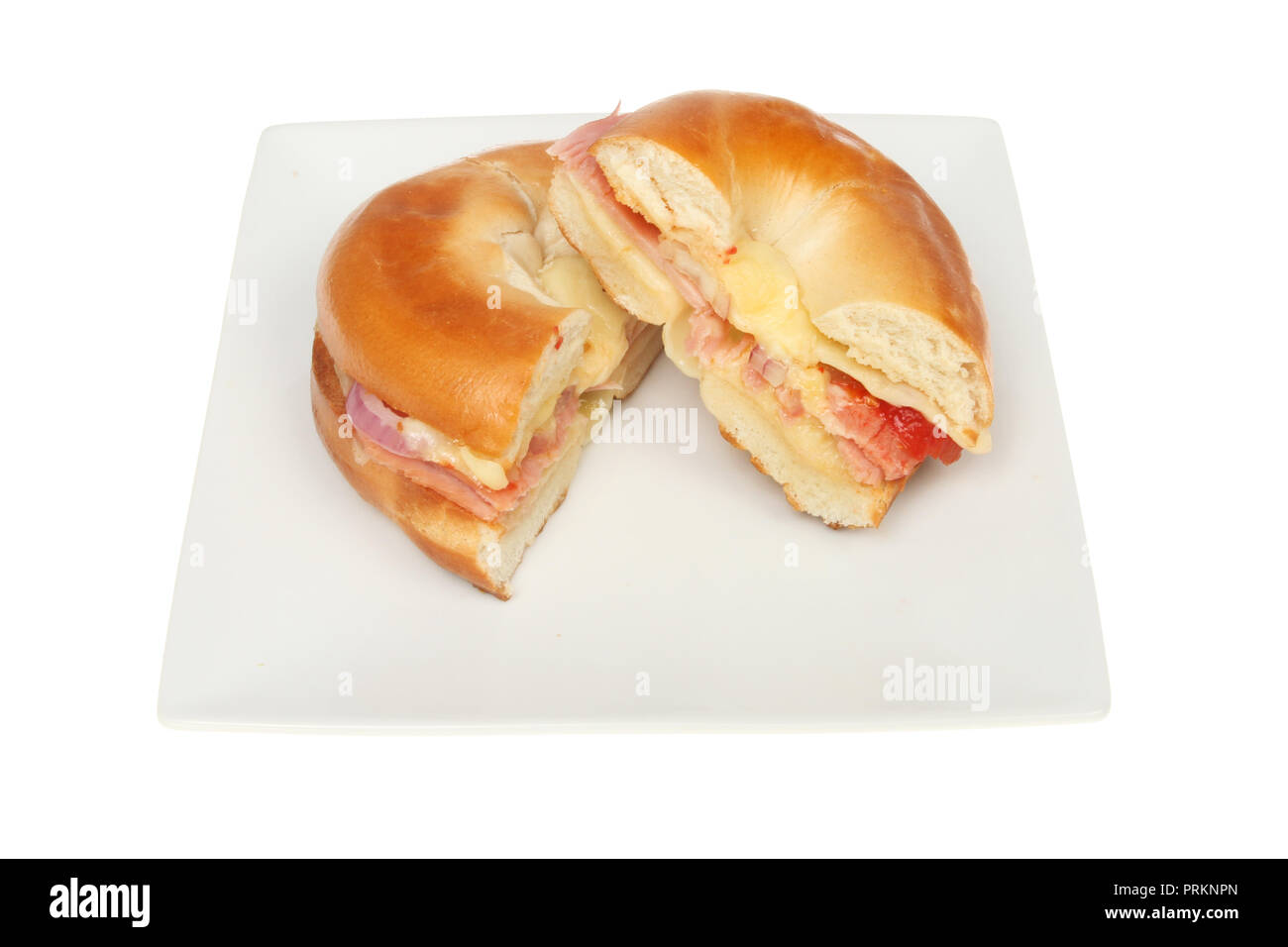 Toasted cheese, ham, onion and tomato bagel cut in half on a plate isolated against white Stock Photo
