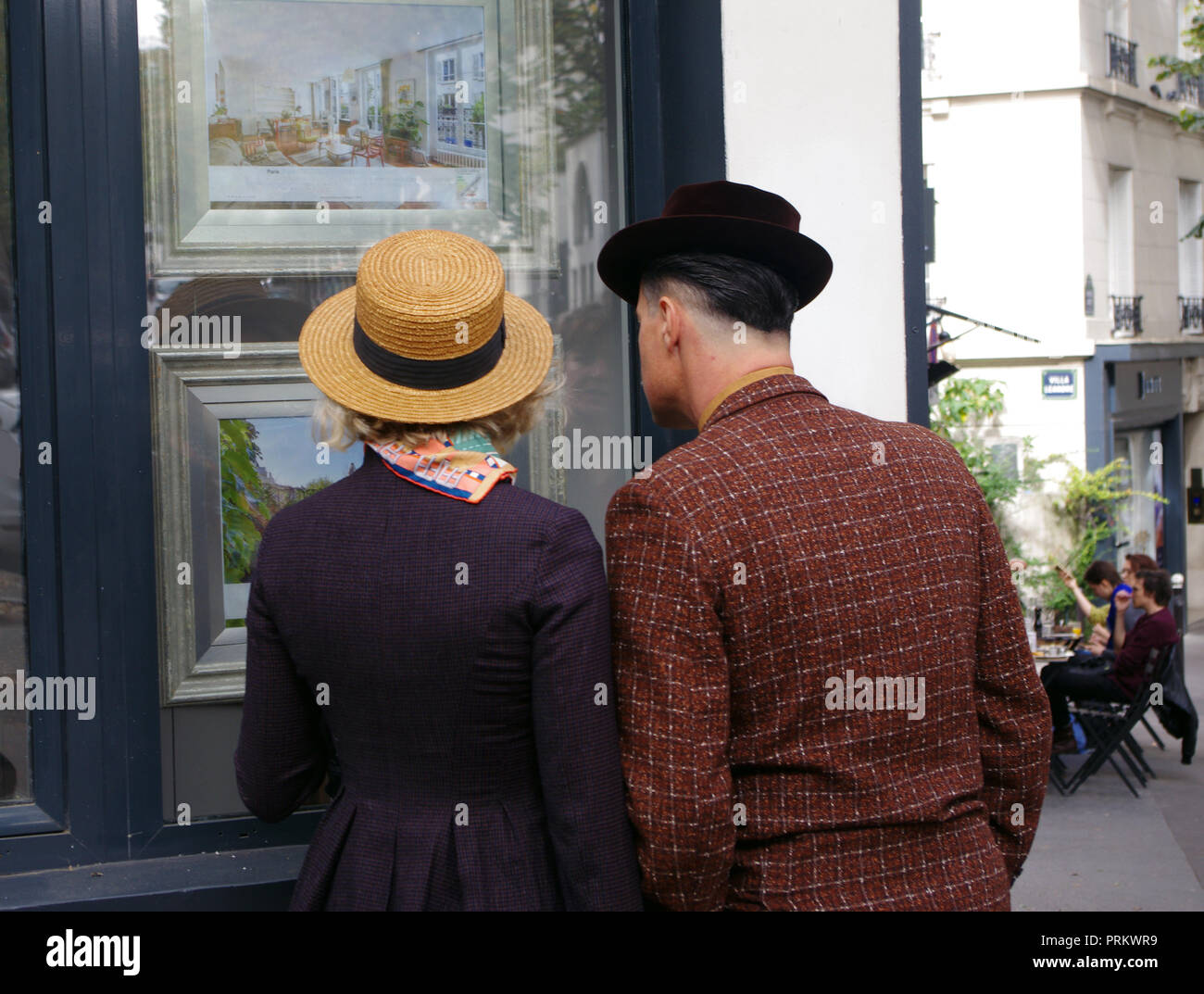 A Parisian couple looks through the window of a store or artist's studio in Montmartre, Paris, France Stock Photo