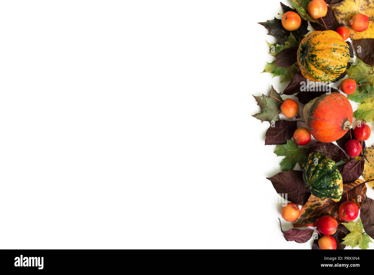 Pumpkins with fall leaves and paradise apples over white background. Top view. Stock Photo