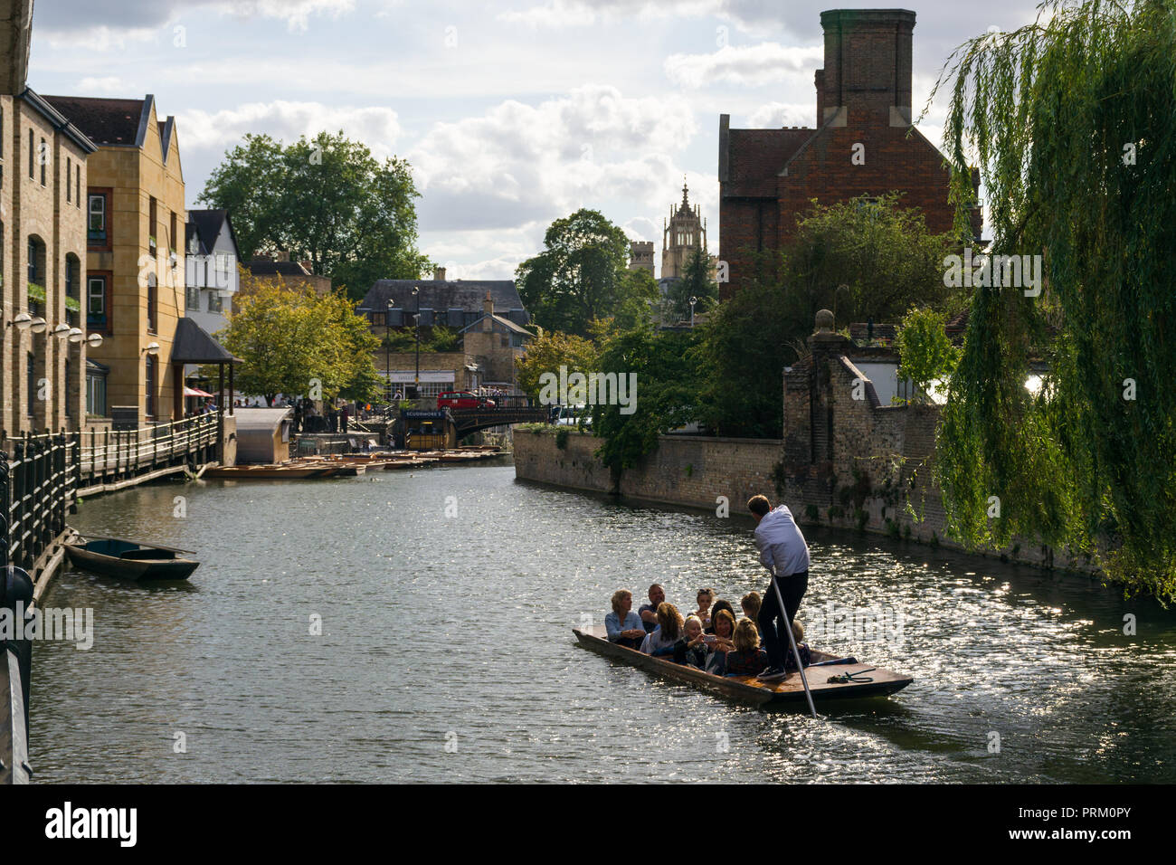 A punt boat with several people aboard on the river Cam heading to Magdalene Bridge on a sunny Summer afternoon, Cambridge, UK Stock Photo