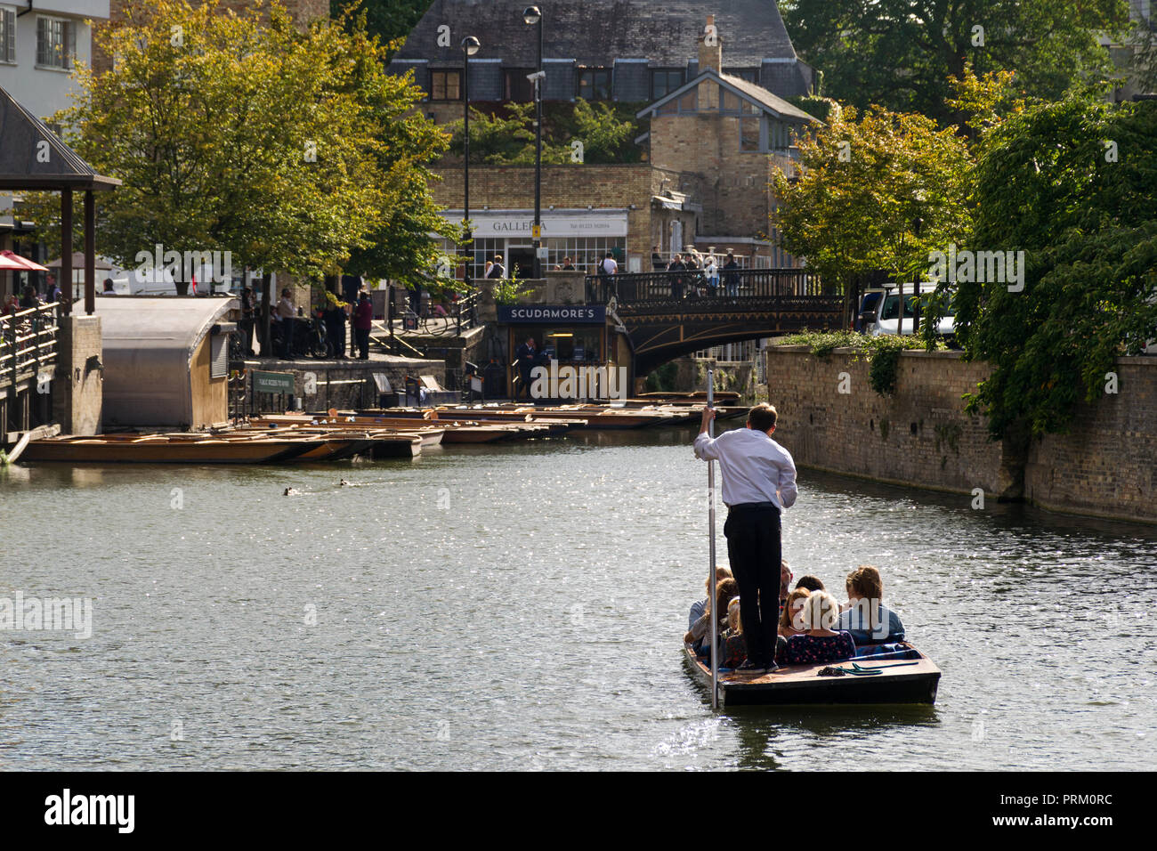 A punt boat with several people aboard on the river Cam heading to Magdalene Bridge on a sunny Summer afternoon, Cambridge, UK Stock Photo