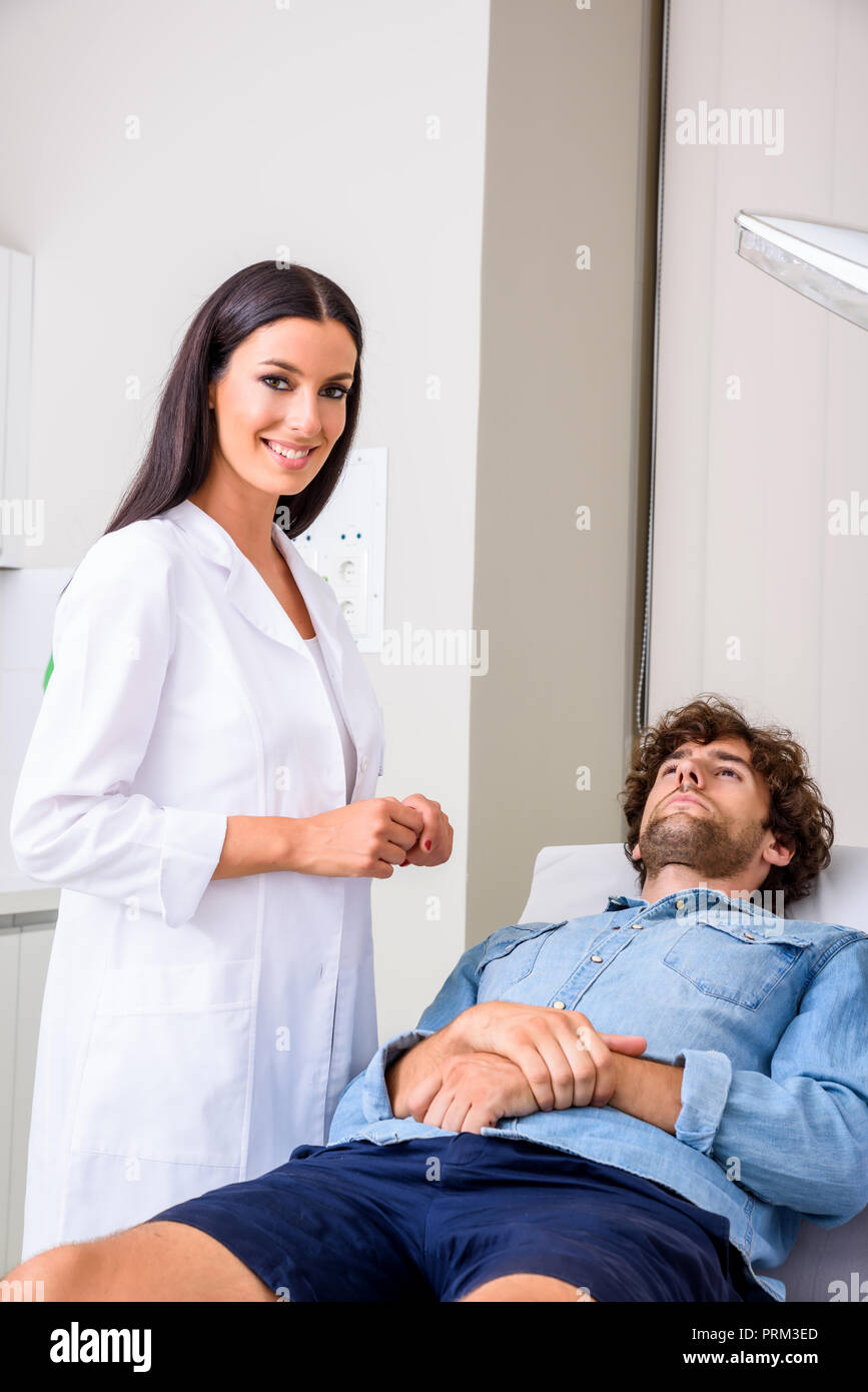 A young male patient in the emergency room getting attended by a female professional physician. Stock Photo