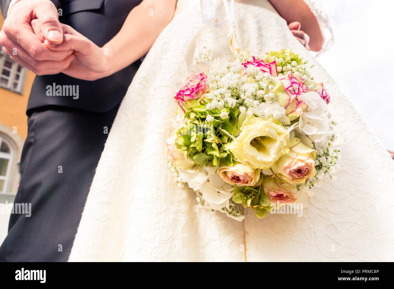 Bride with wedding bouquet holding bridegroom's hand Stock Photo