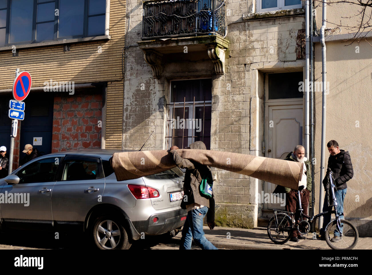 Man carrying a carpet on the streets of Cureghem, Anderlecht, Brussels Stock Photo