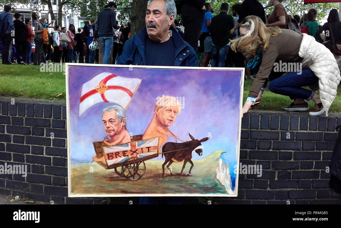 London UK, 2nd July 2016. 'March for Europe', Anti-Brexit protest. An artist, Kaya Mar, holds one of his paintings which depicts Nigel Farage in a cart being pulled by a blindfolded donkey and driven by Boris Johnson. Stock Photo