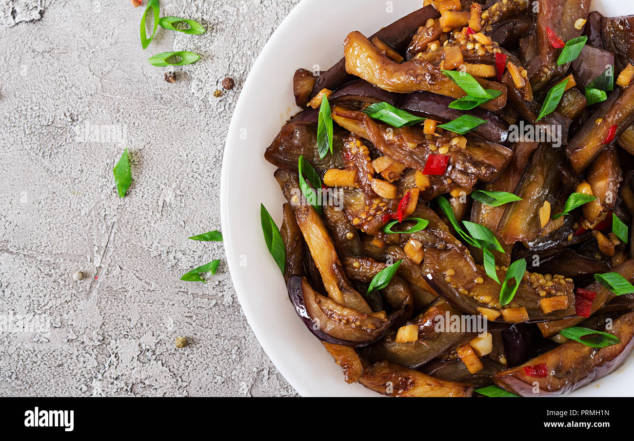 Hot spicy stew eggplant in Korean style with green onion. Aubergine saute. Vegan food. Flat lay. Top view Stock Photo