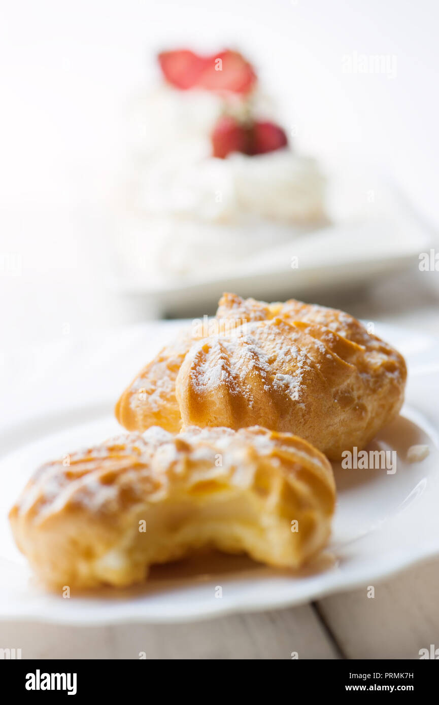 Fresh eclairs with cream on white plate. Stock Photo