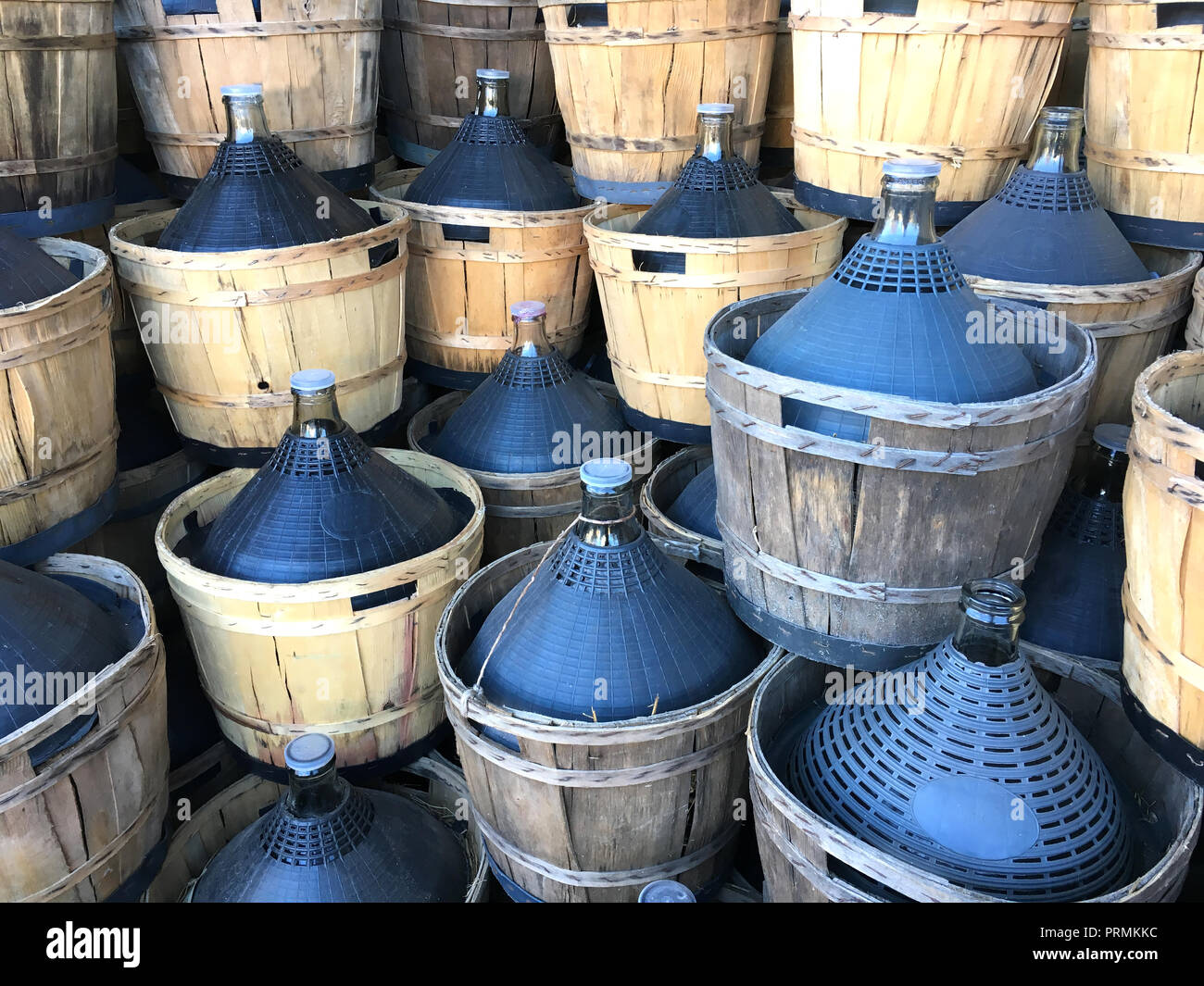 wine carboys bottles enclosed in wickerwork outside at farm Stock Photo