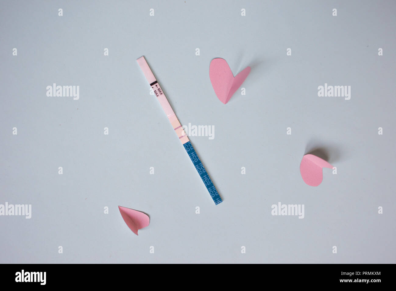 Positive pregnancy test with two strips and pink hearts. blue background, copy space Stock Photo