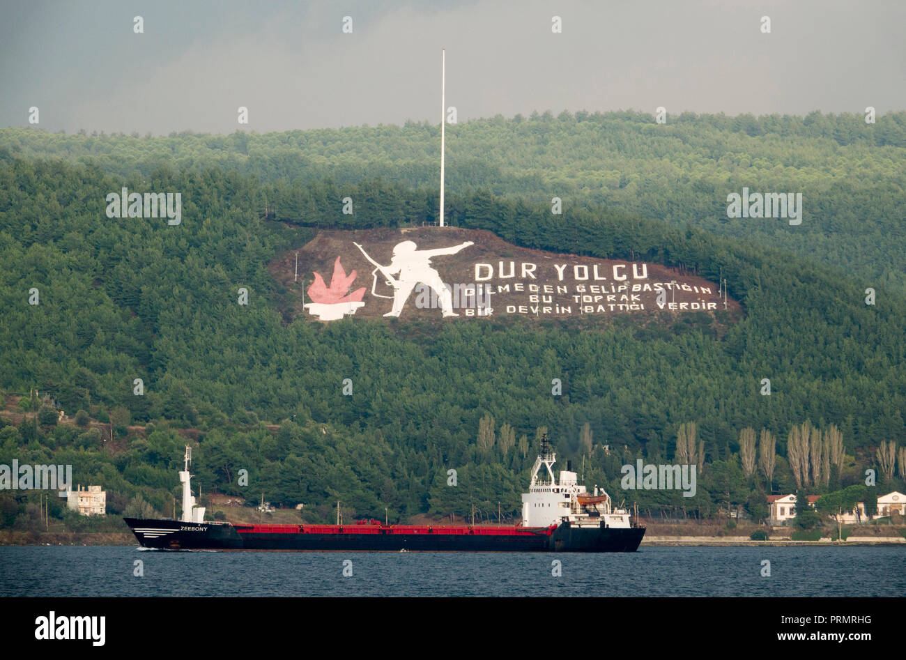 Freight ship passes the Dur Yolcu memorial on the Gallipoli Peninsula in Turkey Stock Photo