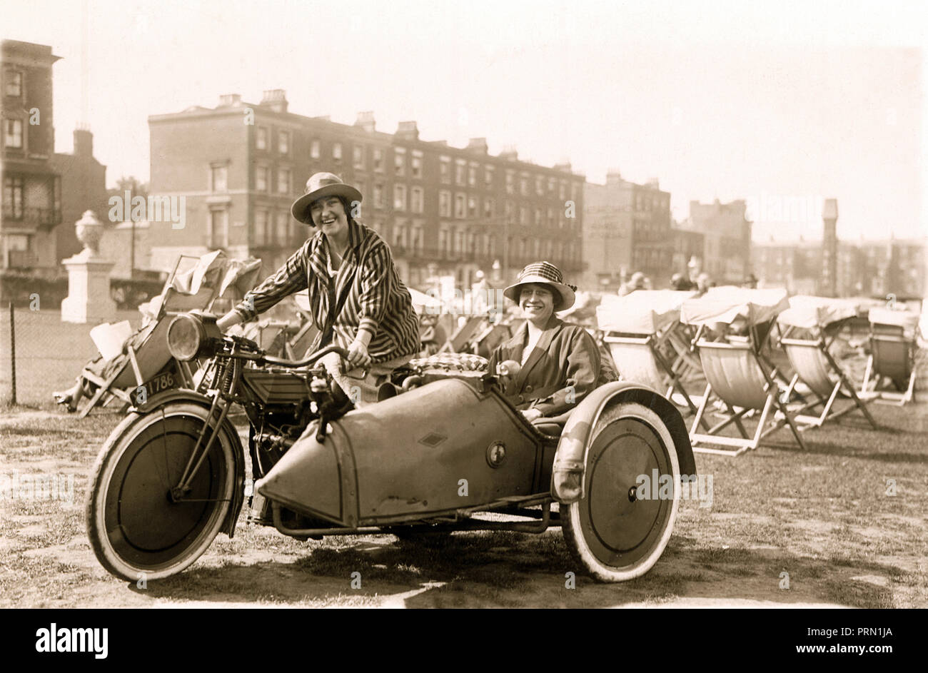 Two stylish ladies pose for photograph on a veteran motorcycle & sidecar combination at the seaside, circa 1915 Stock Photo