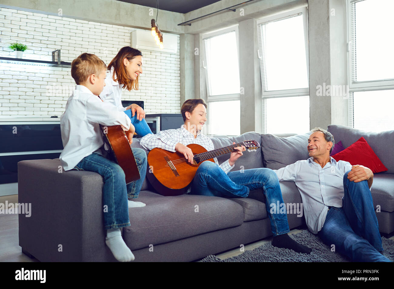 Happy family with guitar singing songs sitting in the room Stock Photo