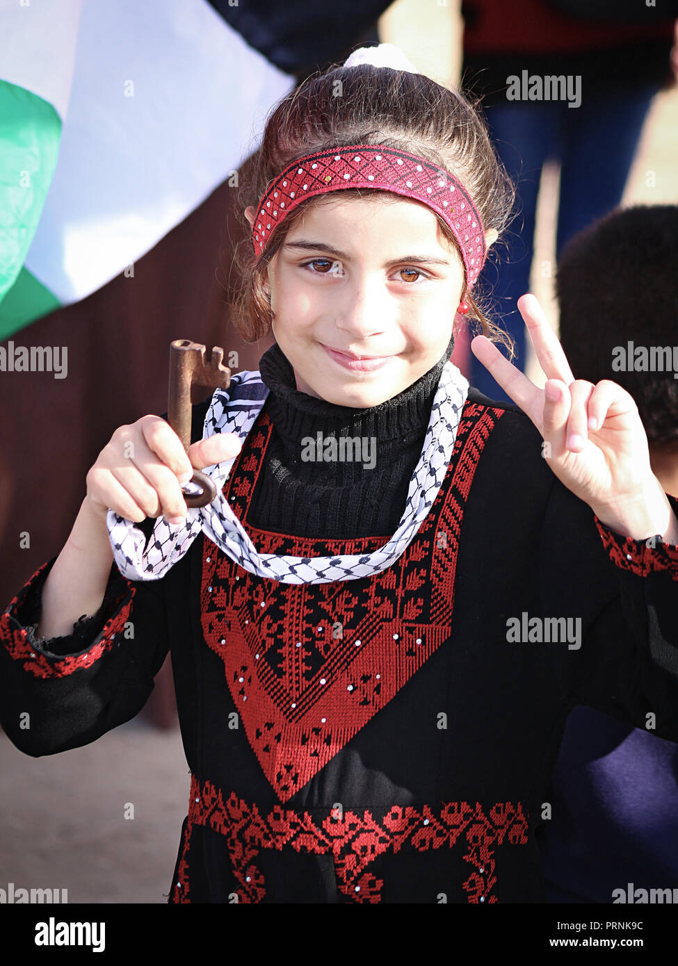 Little Palestinian girl with traditional cloth, holding up a key of return Stock Photo