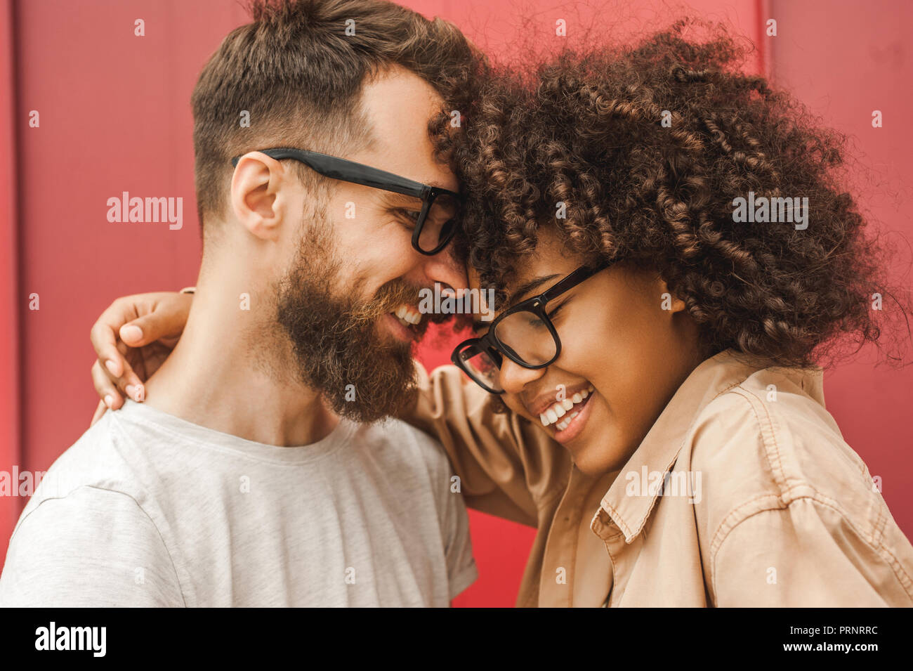 happy young multicultural couple in eyeglasses hugging on street Stock Photo