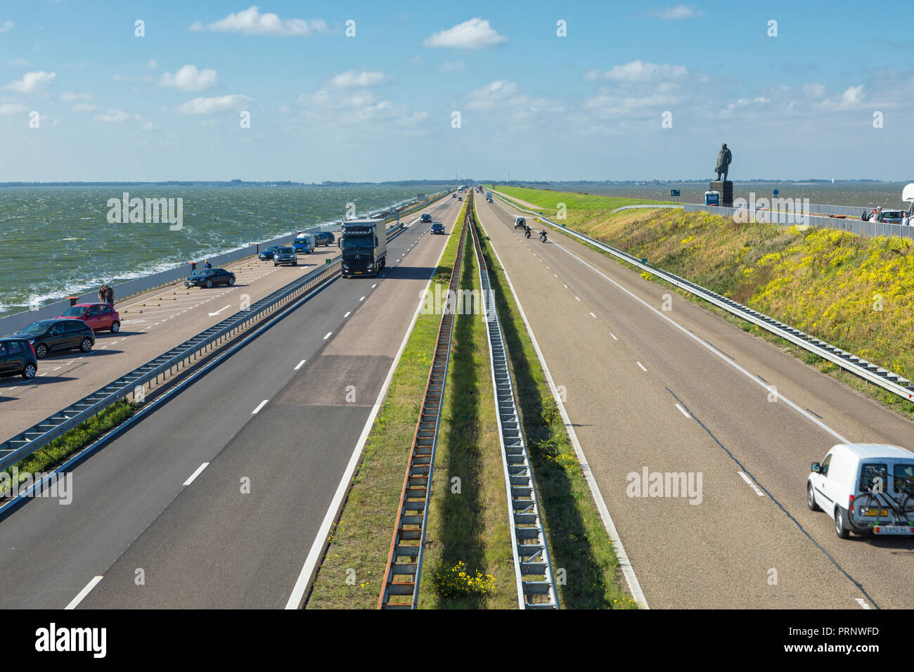 Motorway A7 on Afsluitdijk, a dam separating the North Sea from the Ijsselmeer lake. View from bridge at Breezanddijk, an artificial island. Stock Photo