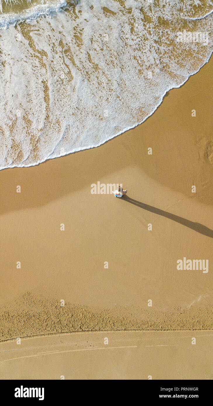 aerial view of young woman standing on sandy beach in front of wavy sea, Ashdod, Israel Stock Photo