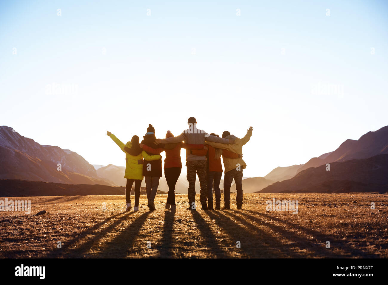 Group of friends against sunset mountains Stock Photo