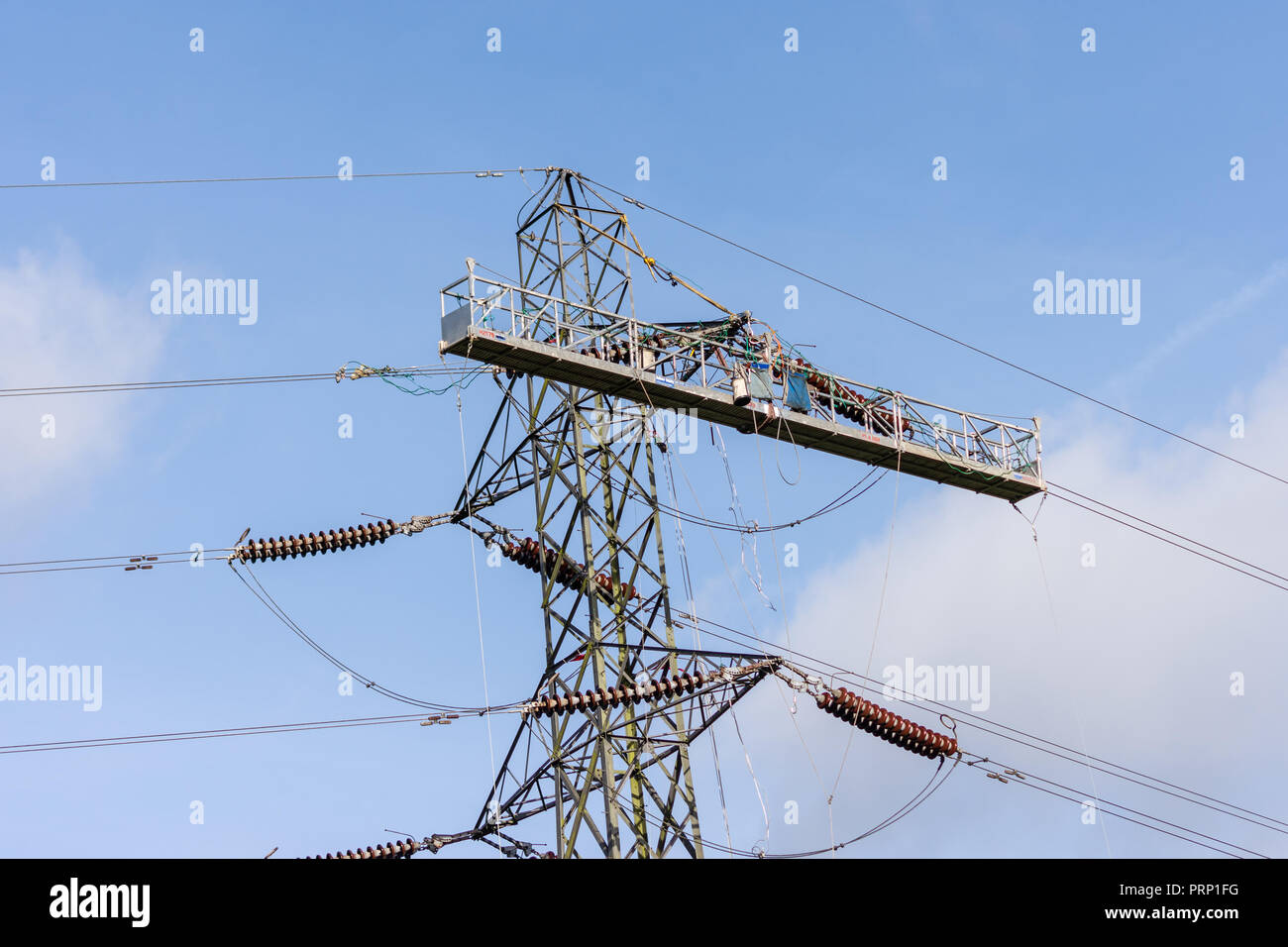 A temporary work platform attached to an electricity pylon for workers to carry out power line replacement Stock Photo