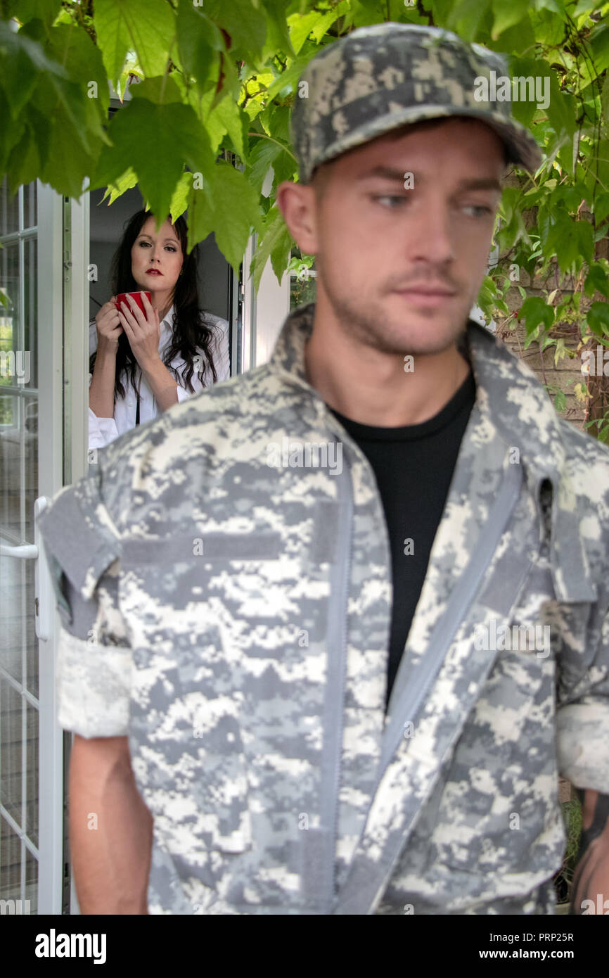 A soldier in cammies, camouflage uniform and hat leaving as wife looks
