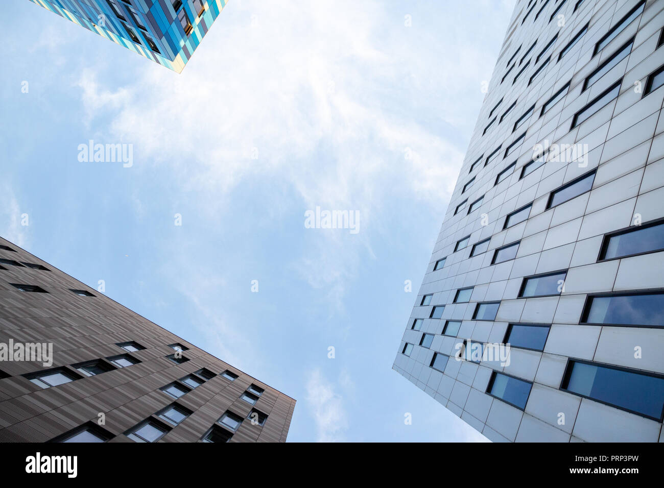 Looking up at blue sky with tall buildings framing the shot Stock Photo