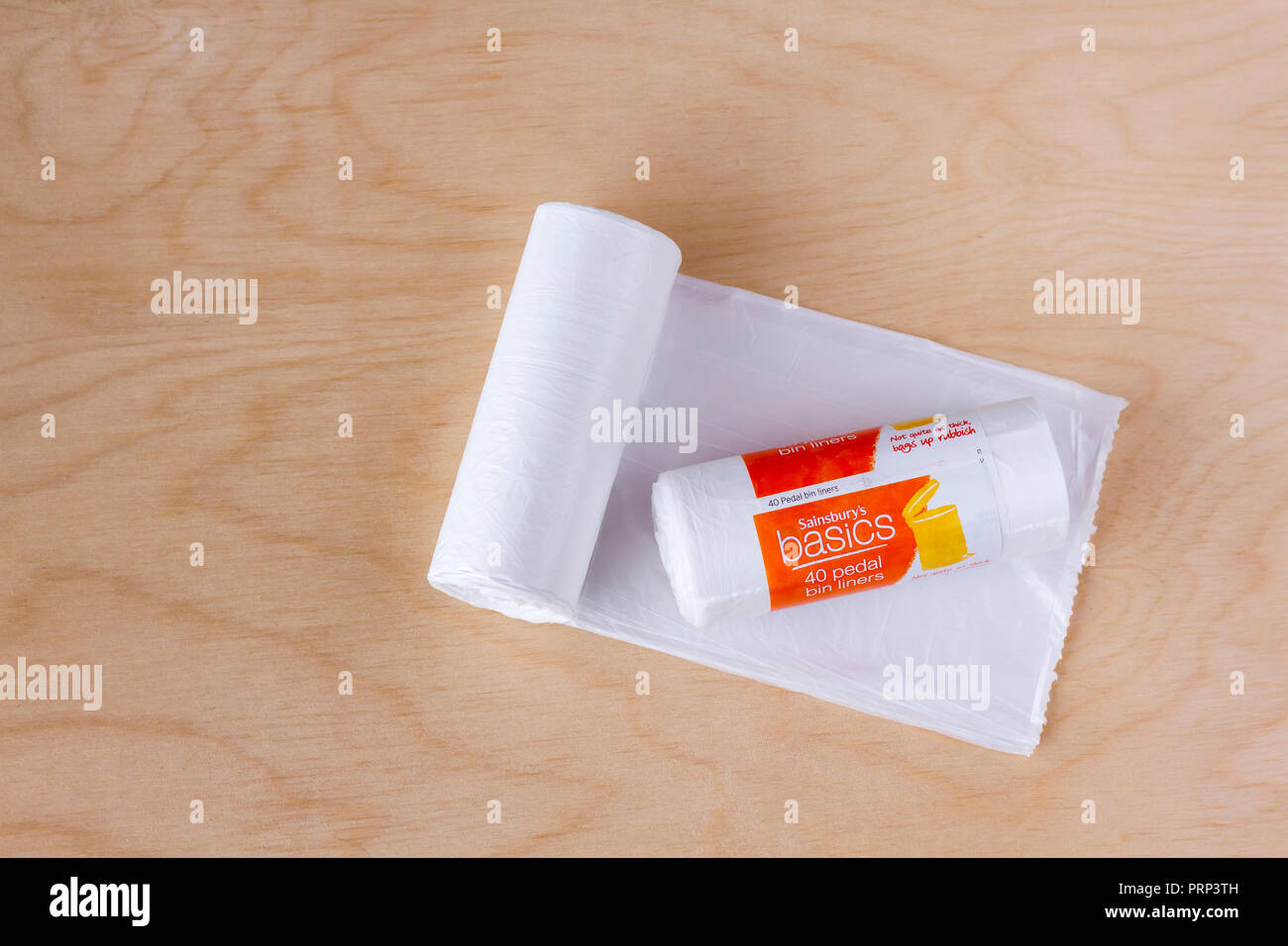 Sainsbury's Basics plastic pedal bin liner roll on a light wood background Stock Photo