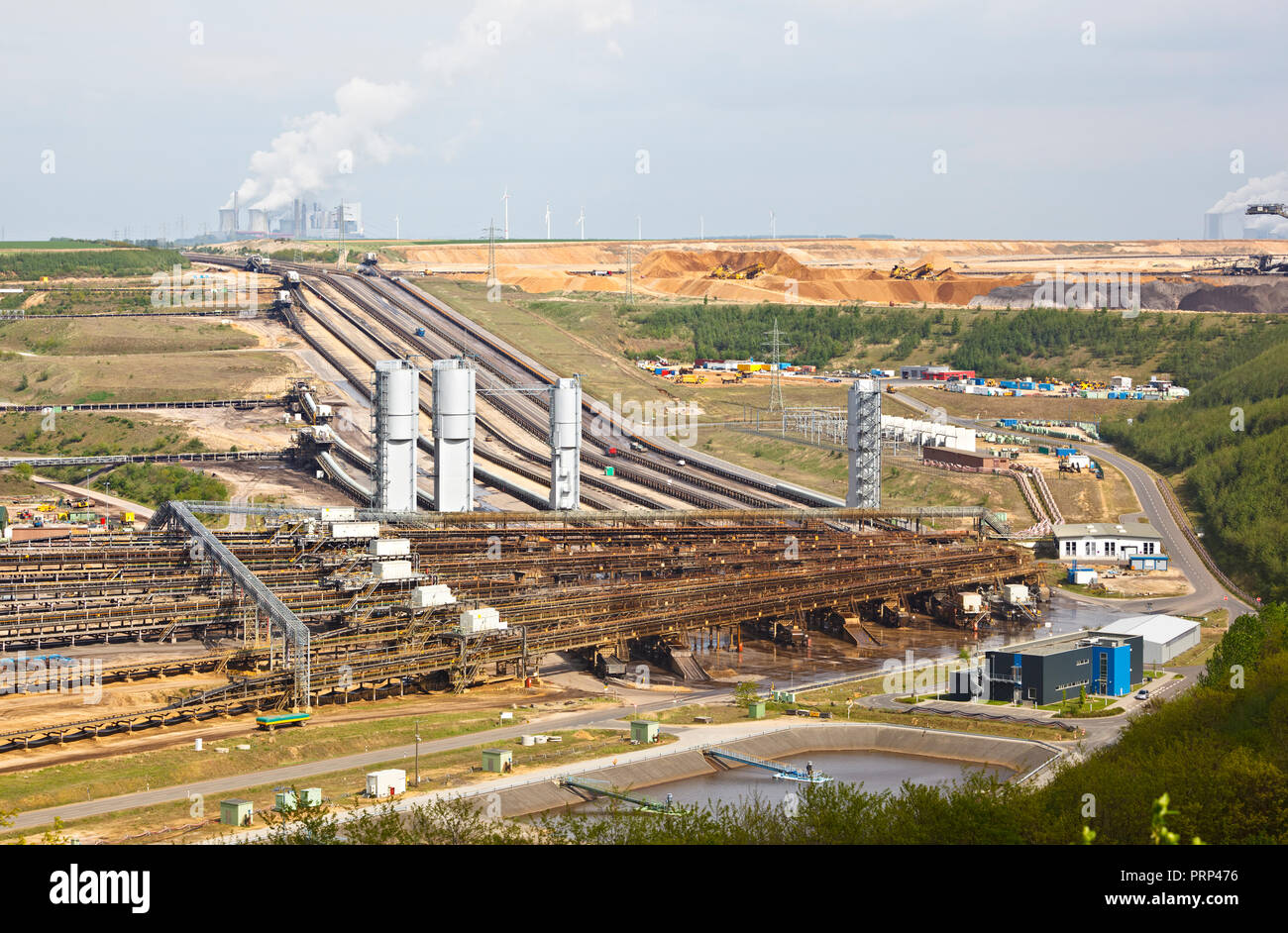 A brown coal pit mine with conveyor belts leading to a distant coal power station. Stock Photo