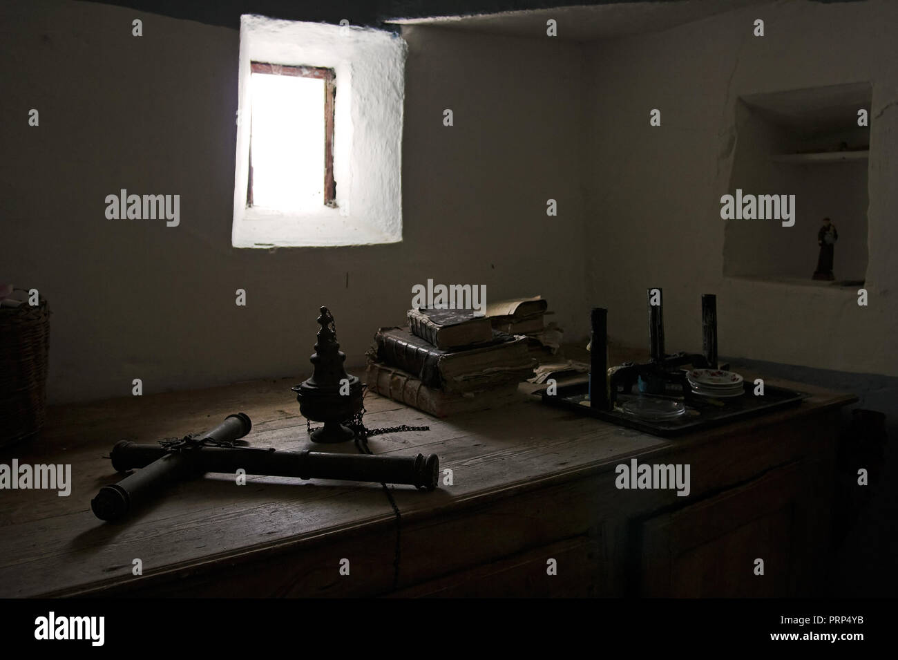 Humble sacristy of a secular chapel in southern Portugal seeing an old bible, books, metal cross and other articles of Catholic mass. Photograph taken Stock Photo