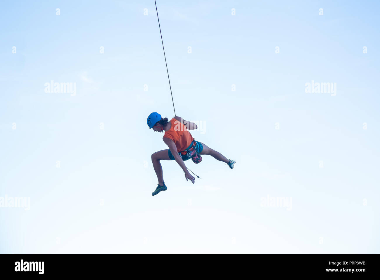 View of man in hardhat hanging on rope while doing rappel and showing ...