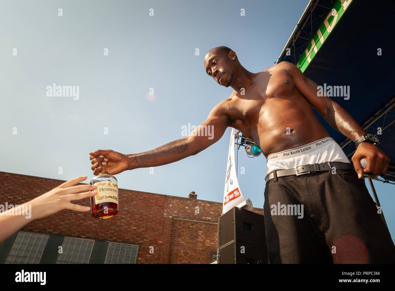 Freddie Gibbs passing Hennessy bottle to audience member during a concert in Chicago in 2010. Stock Photo