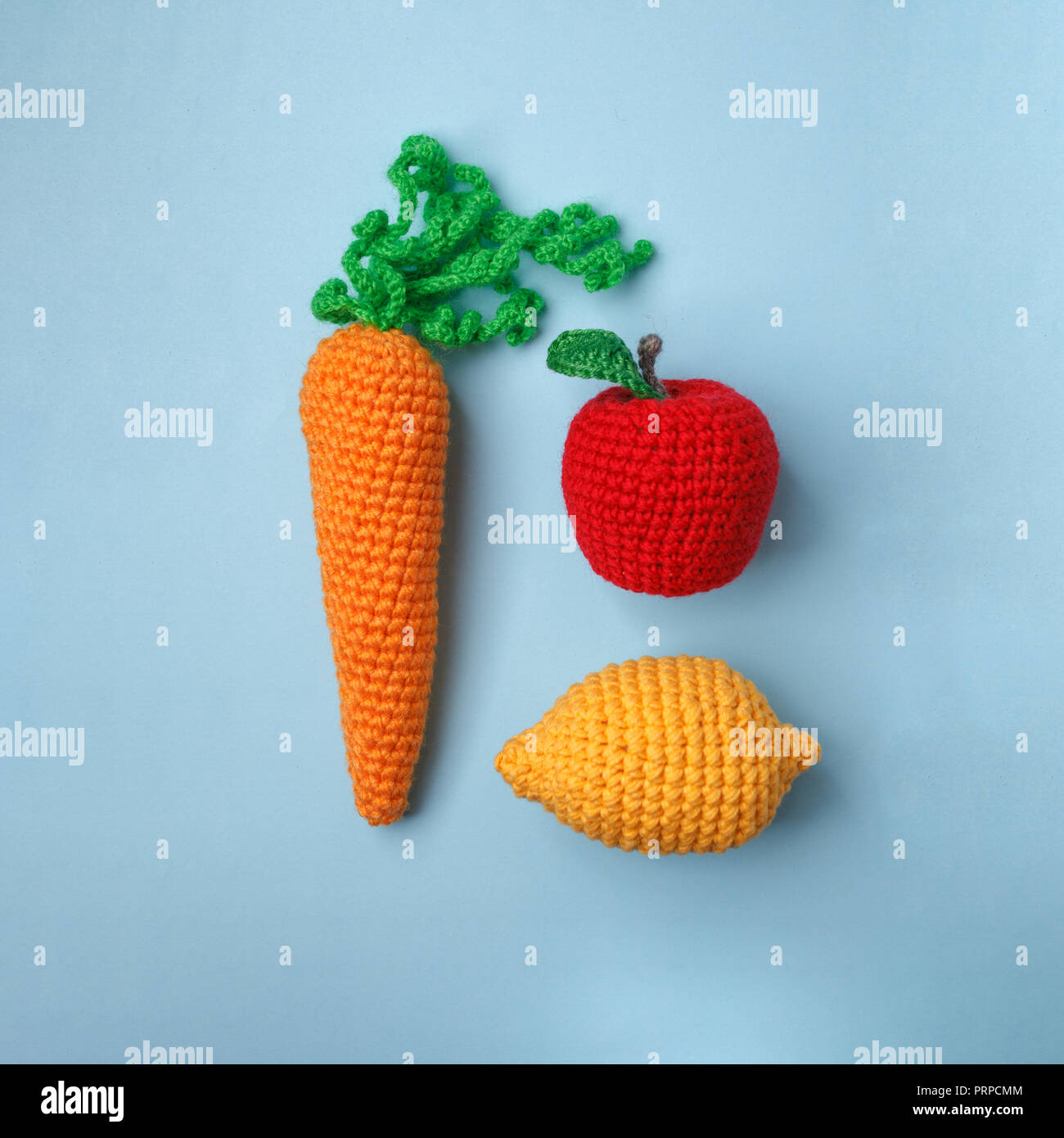 set of knitted toys lemon, carrot, apple on blue background. Earlier tactile development of children, craft toys, vegetarian menu concept Stock Photo