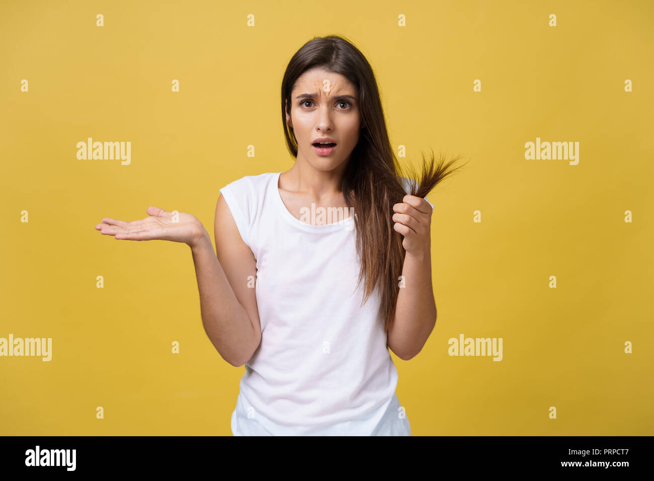 Woman hand holding her long hair with looking at damaged splitting ends