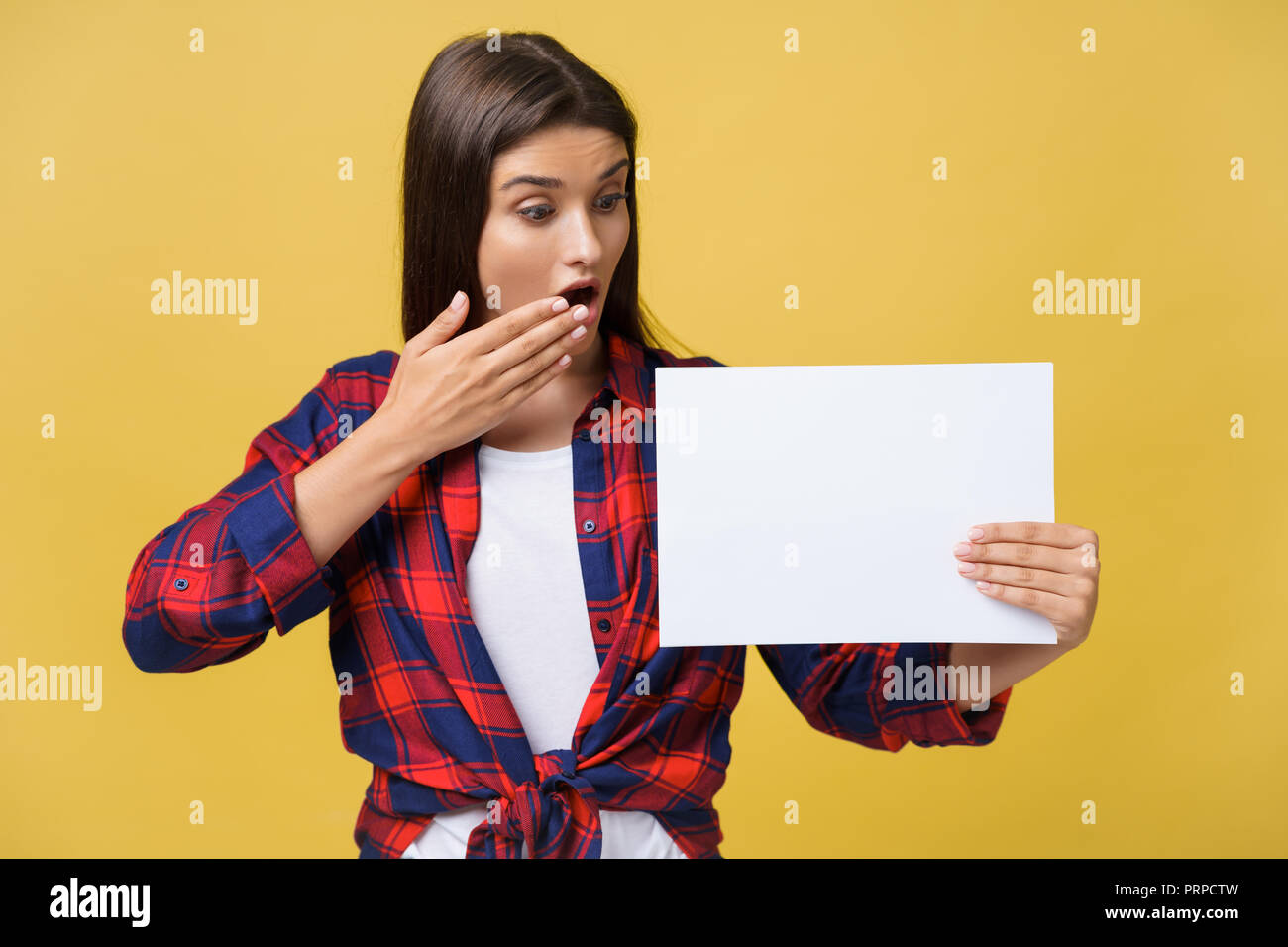 Amazement or surprised female with blank white panel, isolated on yellow background. Stock Photo