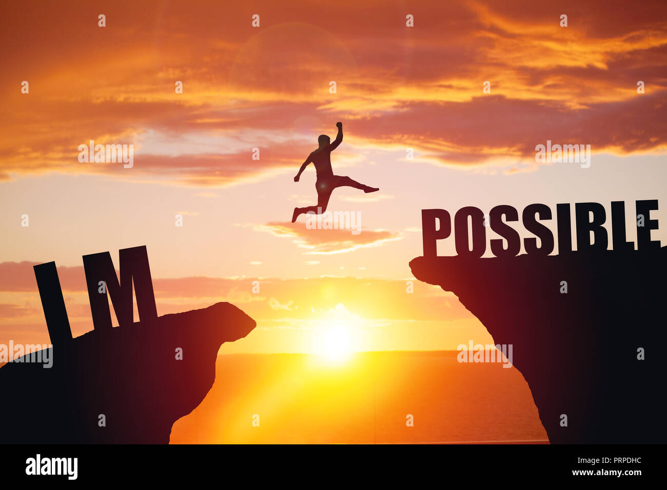 Man jumping over impossible or possible over cliff on sunset background Stock Photo