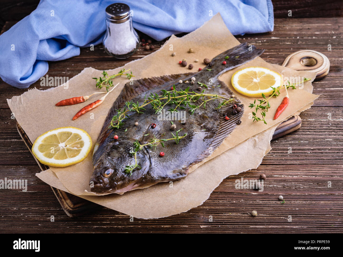 Raw flounder plaice fish (flatfish). Cooking process concept. Flounder fish with spices, lemon