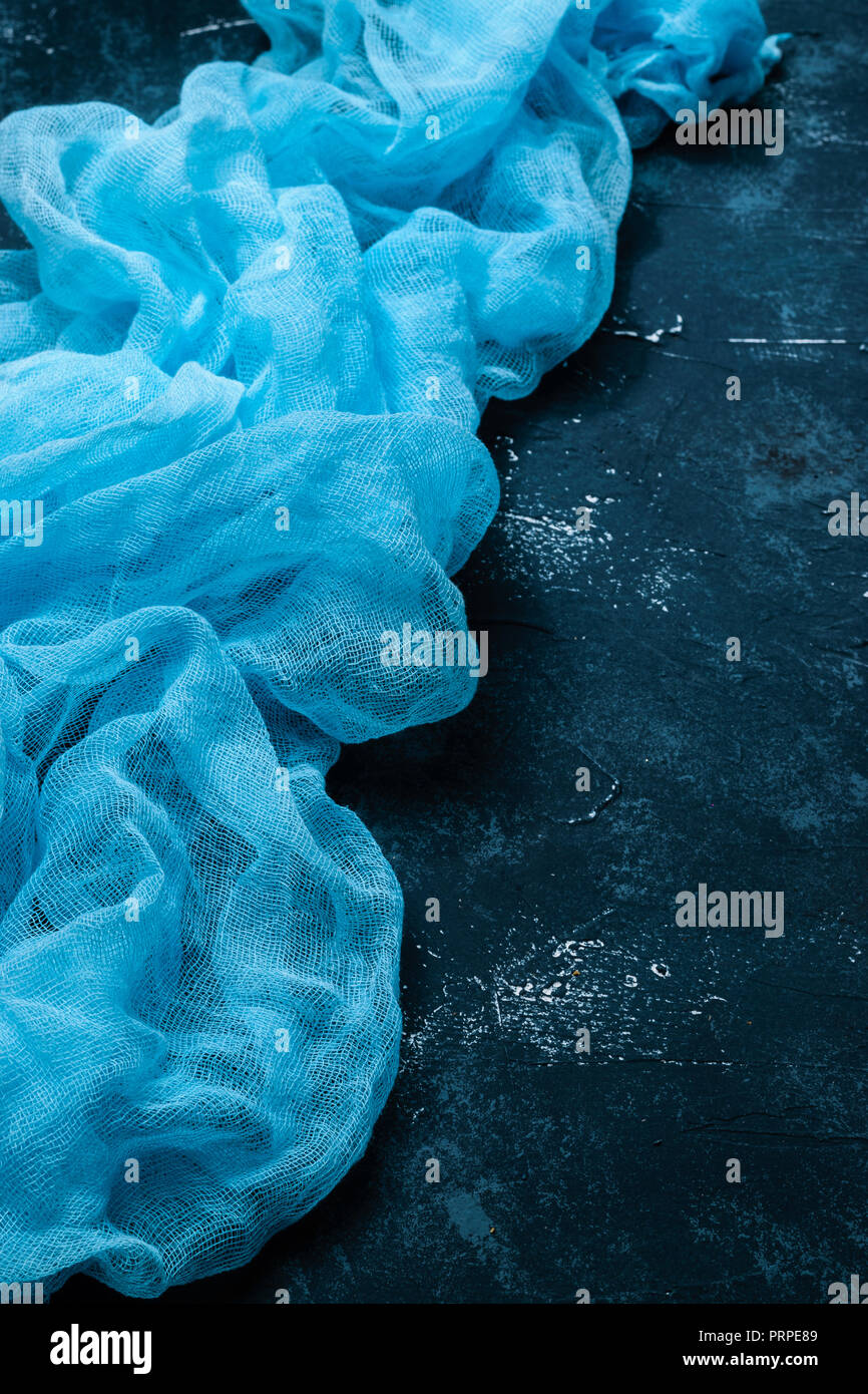 Handmade dyed textured gauze fabric background. Blue colored on concrete background. Table