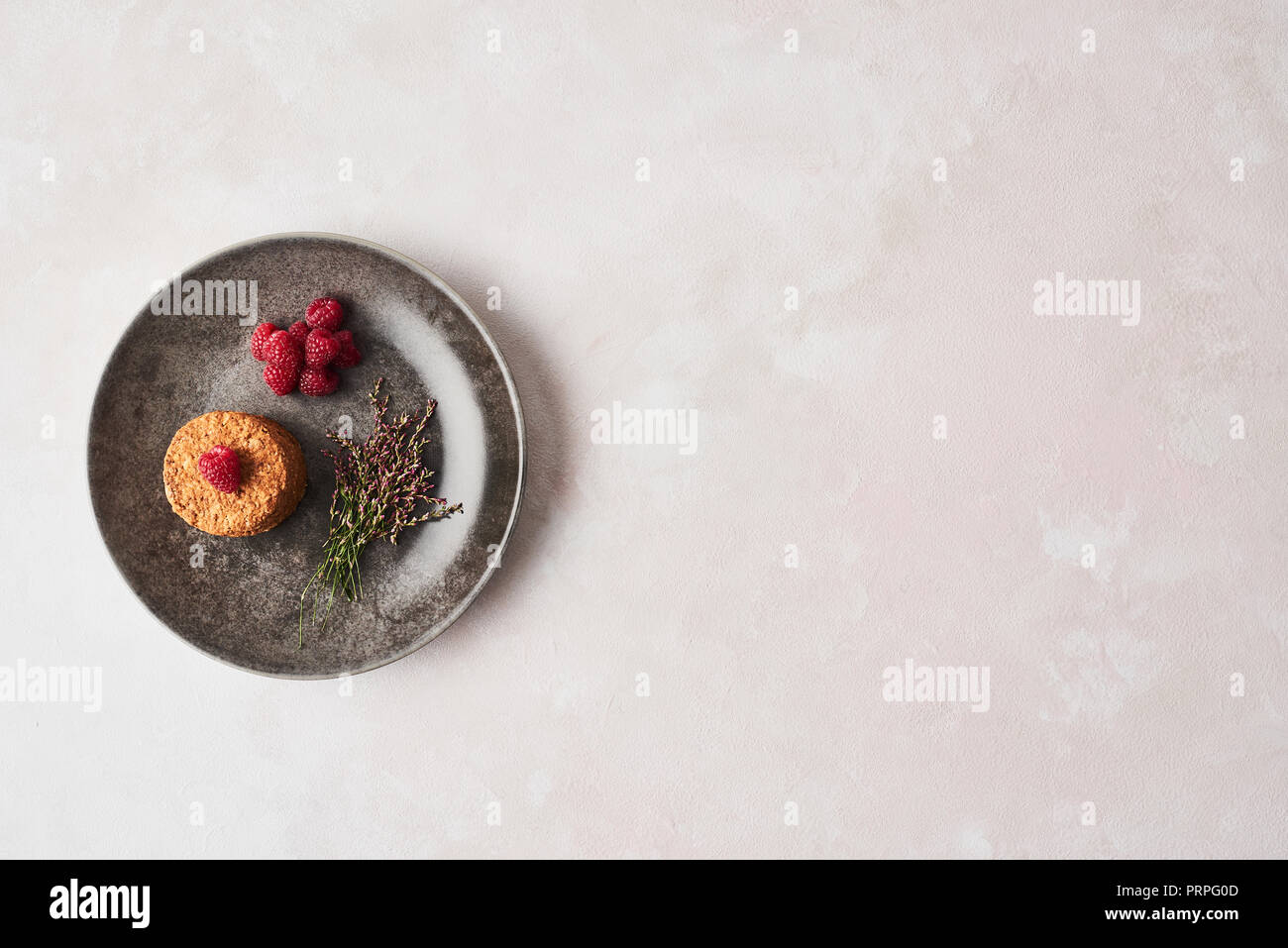 Whole grain cookies with raspberries in a dark rustic plate on pink background. Top view with copy space. Stock Photo