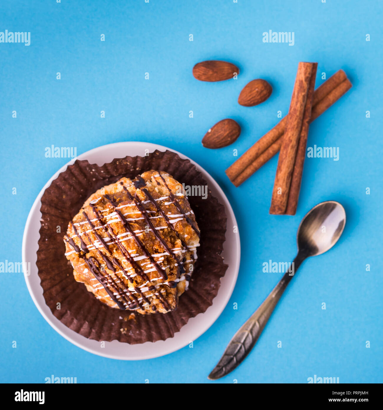 Delicious small cake dessert with caramel and chocolate. Close up view. Decorated with cinnamon sticks and almond nuts. Bright blue modern  background Stock Photo