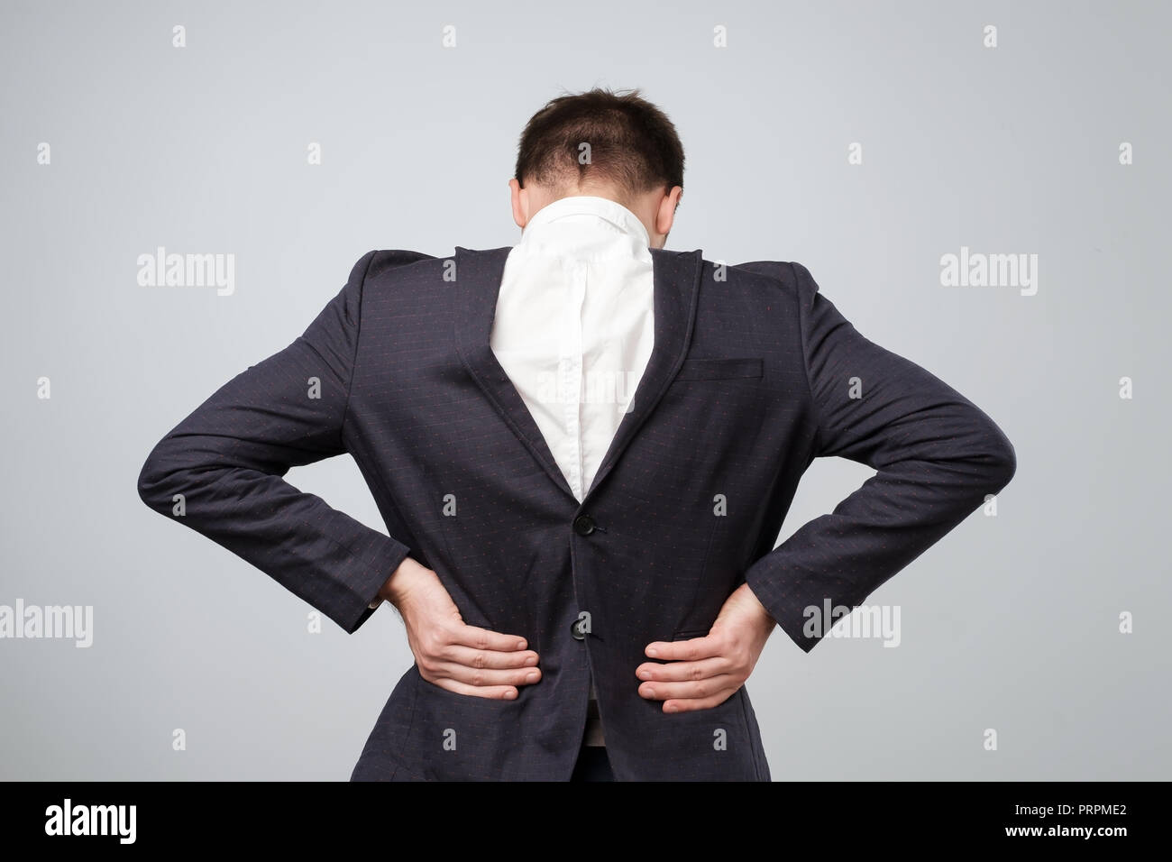 Studio shot of a mature caucasian man wearing his suit on backwards, gray background Stock Photo