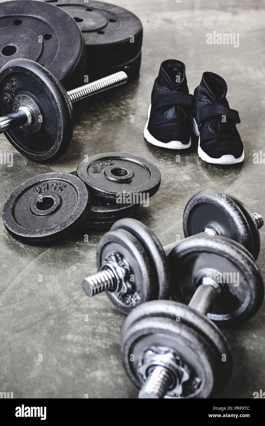 dumbbells and barbell with weight plates and sneakers on concrete floor Stock Photo Alamy