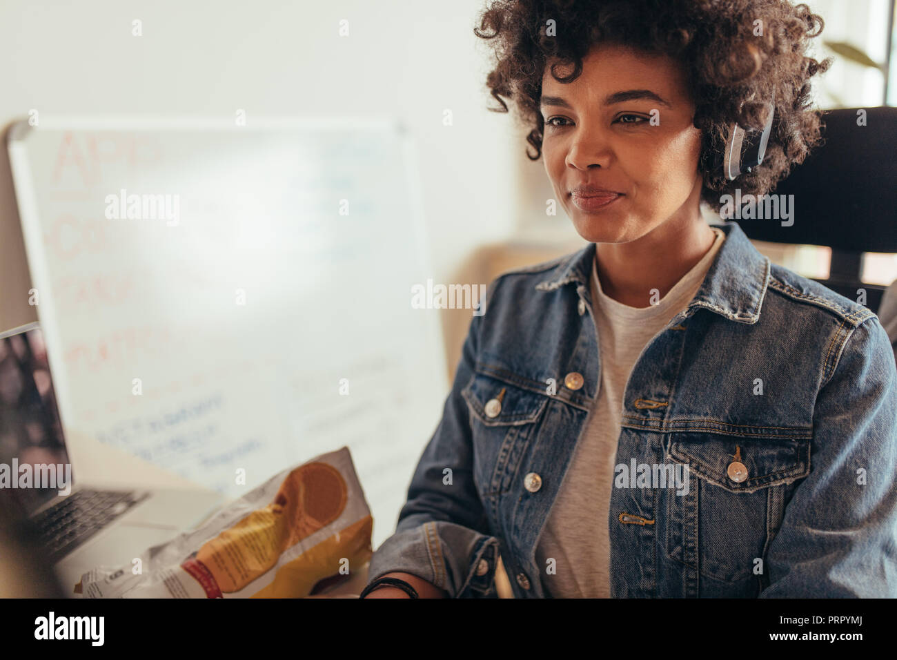 Portrait of african woman working on computer. Female computer programmer working at tech startup. Stock Photo