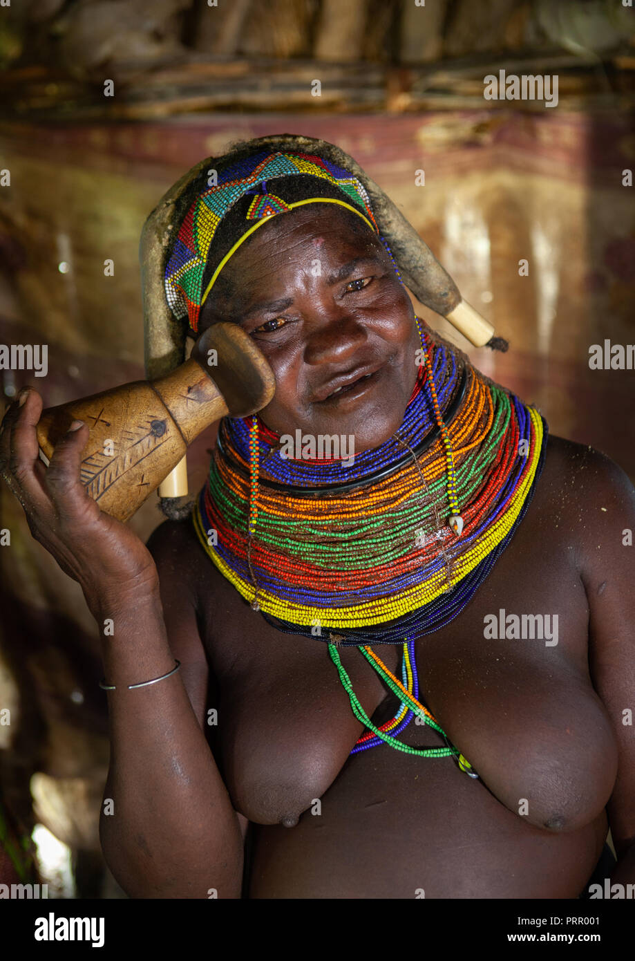 Mumuhuila tribe woman showing how to use a wooden  headrest, Huila Province, Chibia, Angola Stock Photo