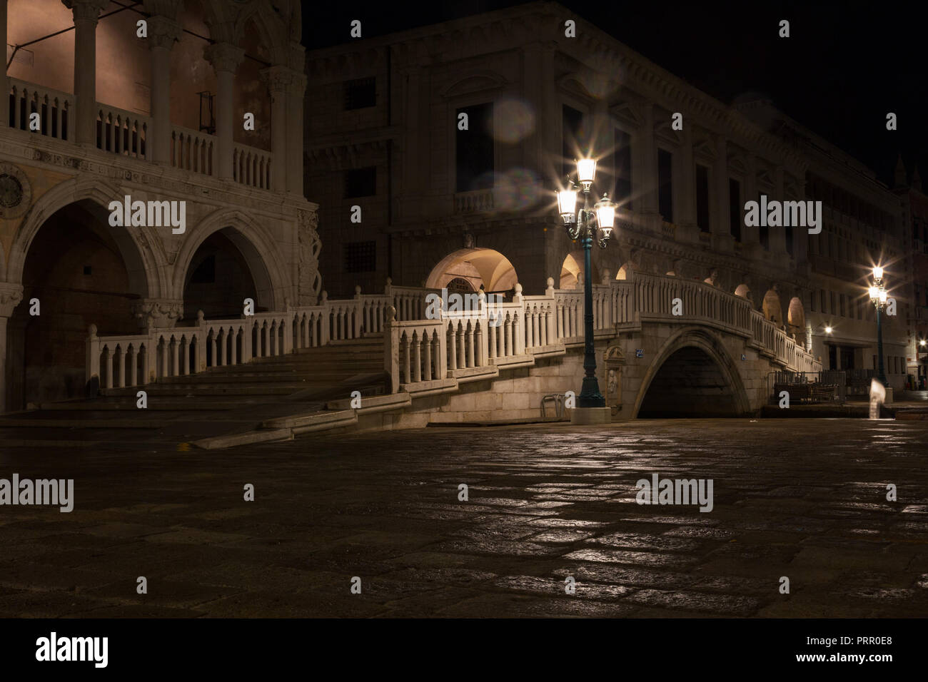 bridge via the Palace channel, a lamp and a wall of Doges Palace at night during a rain, Venice Stock Photo